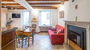 Ein gemütliches Wohnzimmer mit Kamin, einem Essbereich mit Holztisch und Stühlen sowie einem roten Sofa.