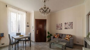 A living room with a sofa, coffee table, and chandelier. - GuestHost - Sweety Apartment near MM Ottaviano (Roma)