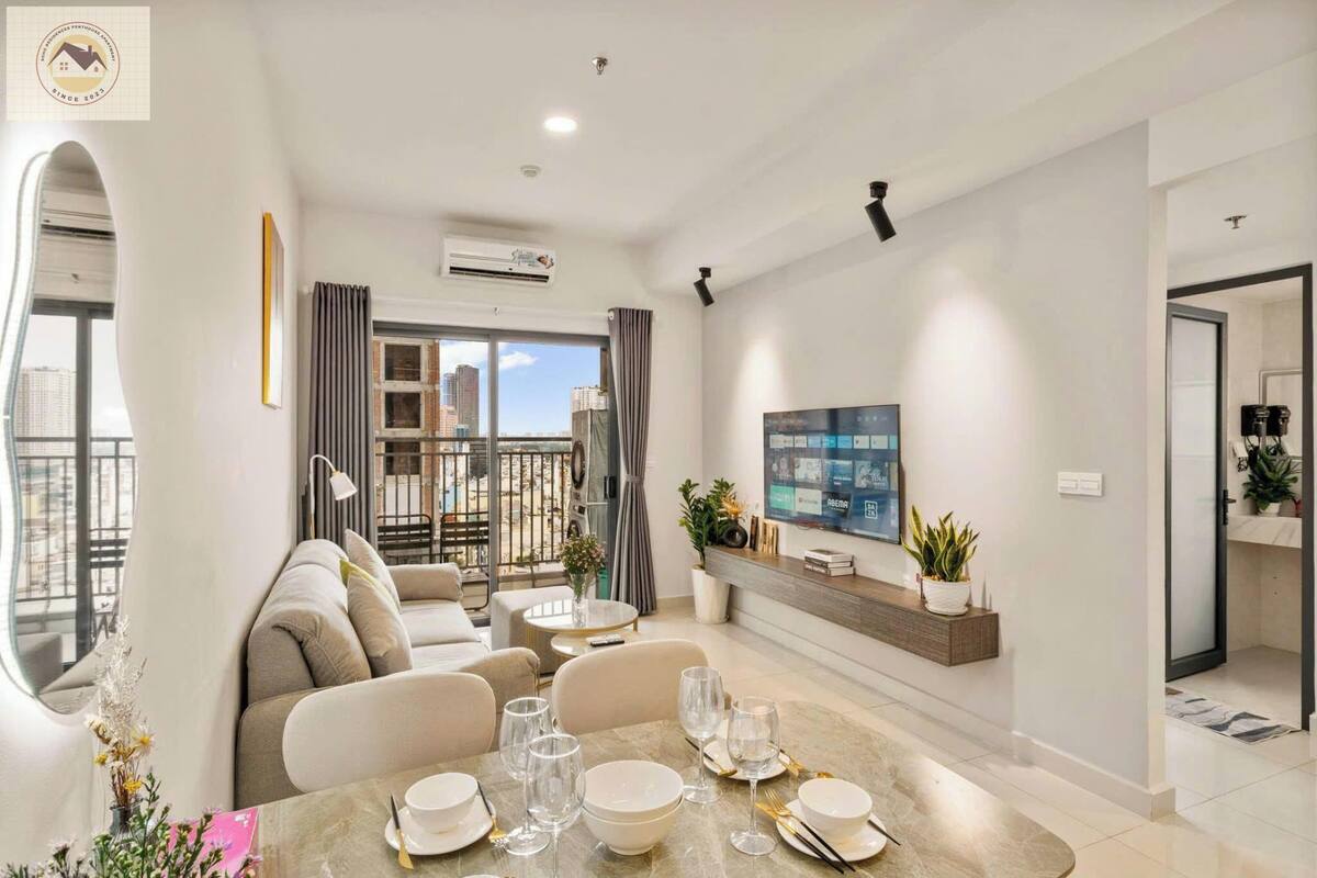 A modern living room with a sofa set, dining table, and a mounted TV.