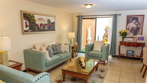 A living room with a green sofa, a coffee table, and a statue. - Posada Doña Lucilia.  Comfort, elegance and beauty.  Your home away from home. (Mixco)