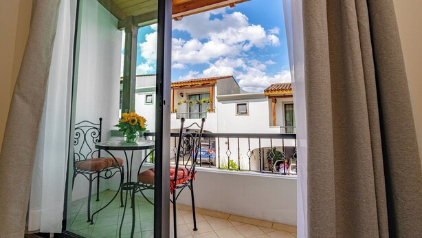 A balcony with a table and chairs, a view of the sky, and a building in the background. - Posada Doña Lucilia.  Comfort, elegance and beauty.  Your home away from home. (Mixco)