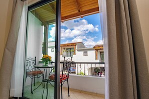 A balcony with a table and chairs, a view of the sky, and a building in the background.