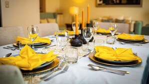 A dining table set with yellow napkins, plates, and cutlery, with candles and glasses on the table.