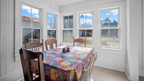 A dining room with a table covered in a colorful tablecloth, surrounded by wooden chairs. - Pet Friendly • Fenced Yard • Near Statesboro (Metter)