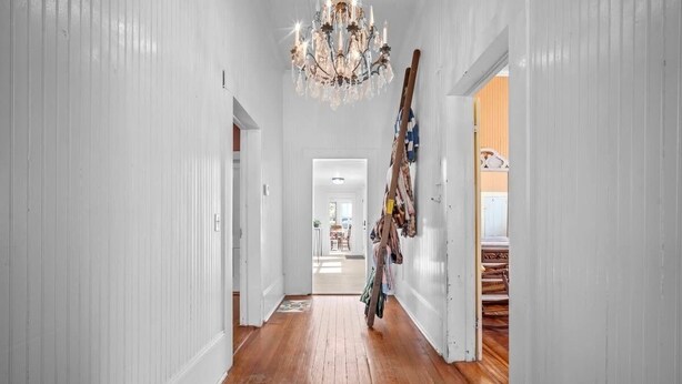 A hallway with wooden flooring, white walls, and a chandelier. - Pet Friendly • Fenced Yard • Near Statesboro (Metter)