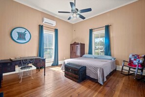 Un dormitorio con cama, escritorio, silla, maleta y mecedora.