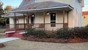 Charming single-story home with a gabled roof and porch, featuring a colorful quilted design and a well-manicured lawn.