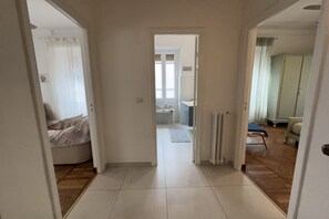 A hallway leading to a bedroom with a bed, a bathroom with a bathtub, and a living area with a sofa.