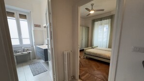 Un dormitorio con cama, radiador, ventilador de techo y ventana.