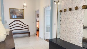 Una habitación con un banco de madera, un espejo grande y un papel tapiz estampado.