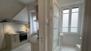 Una cocina moderna con armarios blancos, una estufa a gas y un ventanal con persianas.