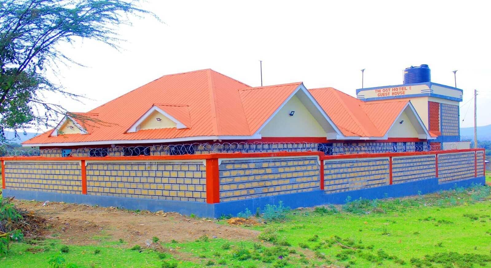 Un hôtel avec un toit rouge, des murs en briques et une enseigne indiquant qu’il s’agit d’une maison d’hôtes.