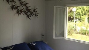 A bedroom with a bed, a window, and a wall decoration. - Chalet grand confort Bassin d'Arcachon - Chalet les solariales (La Teste De Buch)