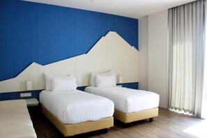 A hotel room with two beds, a blue and white wall design, and a large window with curtains. - Bromo Park Hotel (Probolinggo)