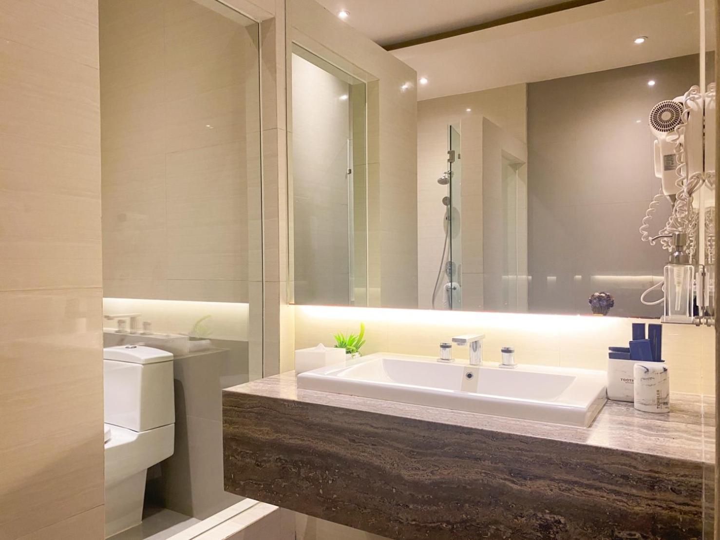 A modern bathroom with a large mirror, a built-in shower, and a marble countertop.