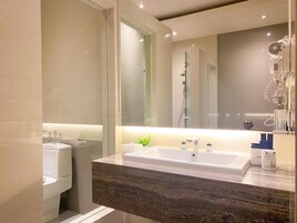 Un baño moderno con un espejo grande, ducha integrada y encimera de mármol.