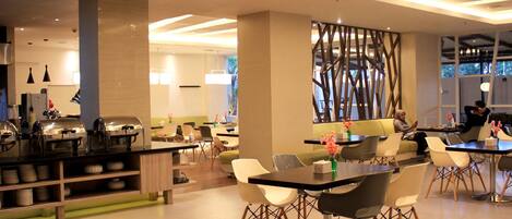 Un área de comedor moderna con buffet, disposición de mesas y sillas, y una pared decorativa.