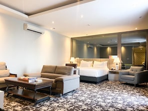 A hotel room with a bed, two armchairs, a sofa, a coffee table, and a large mirror. - Bromo Park Hotel (Probolinggo)