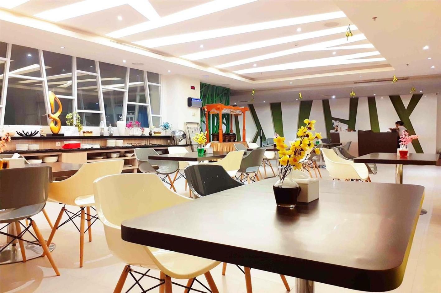 A modern dining area with contemporary furniture, a central table with a vase of yellow flowers, and a large window with a view.