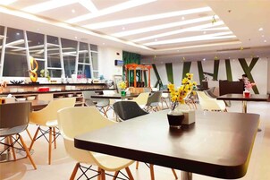 Un comedor moderno con mobiliario contemporáneo, una mesa central con un jarrón de flores amarillas y un ventanal con vistas.