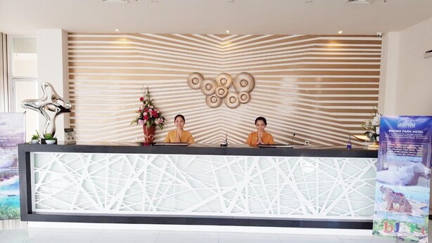 A reception desk with a modern design, featuring a geometric pattern on the counter and a decorative wall with a striped pattern and circular designs. - Bromo Park Hotel (Probolinggo)