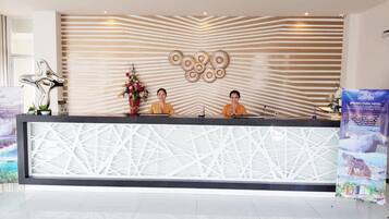 A reception desk with a modern design, featuring a geometric pattern on the counter and a decorative wall with a striped pattern and circular designs.