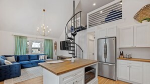 A modern kitchen with white cabinets, a wooden countertop, and a stainless steel refrigerator.