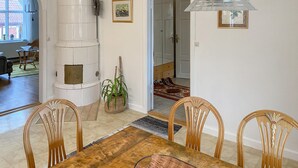 Un espace repas avec une table et des chaises en bois, un objet cylindrique blanc et un luminaire suspendu.