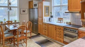 Une cuisine avec des meubles de rangement en bois, un réfrigérateur, une cuisinière et une table à manger avec des chaises.