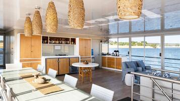 Een moderne keuken met houten kastjes, een bar en grote ramen met uitzicht op een waterpartij.