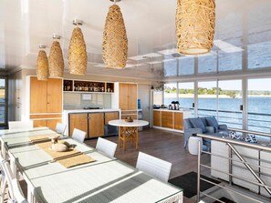 Una cocina moderna con armarios de madera, una zona de bar y grandes ventanales con vistas al agua.