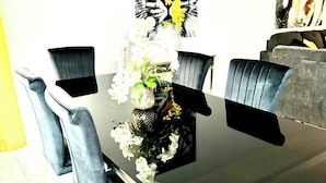 A dining area with a black table, six blue chairs, and a vase with white flowers.