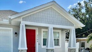 A residential house with a red door, stone pillars, and a garage.