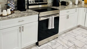 A modern kitchen with white cabinets, a stainless steel microwave, a black oven, and a granite countertop.