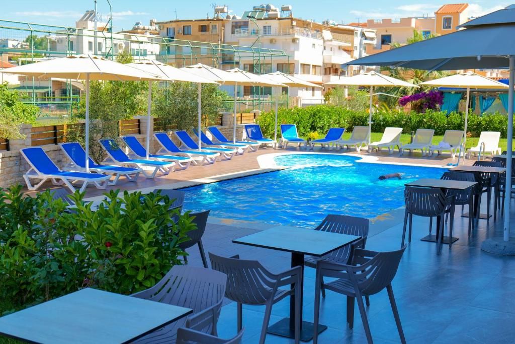 A pool area with lounge chairs and tables, surrounded by buildings.
