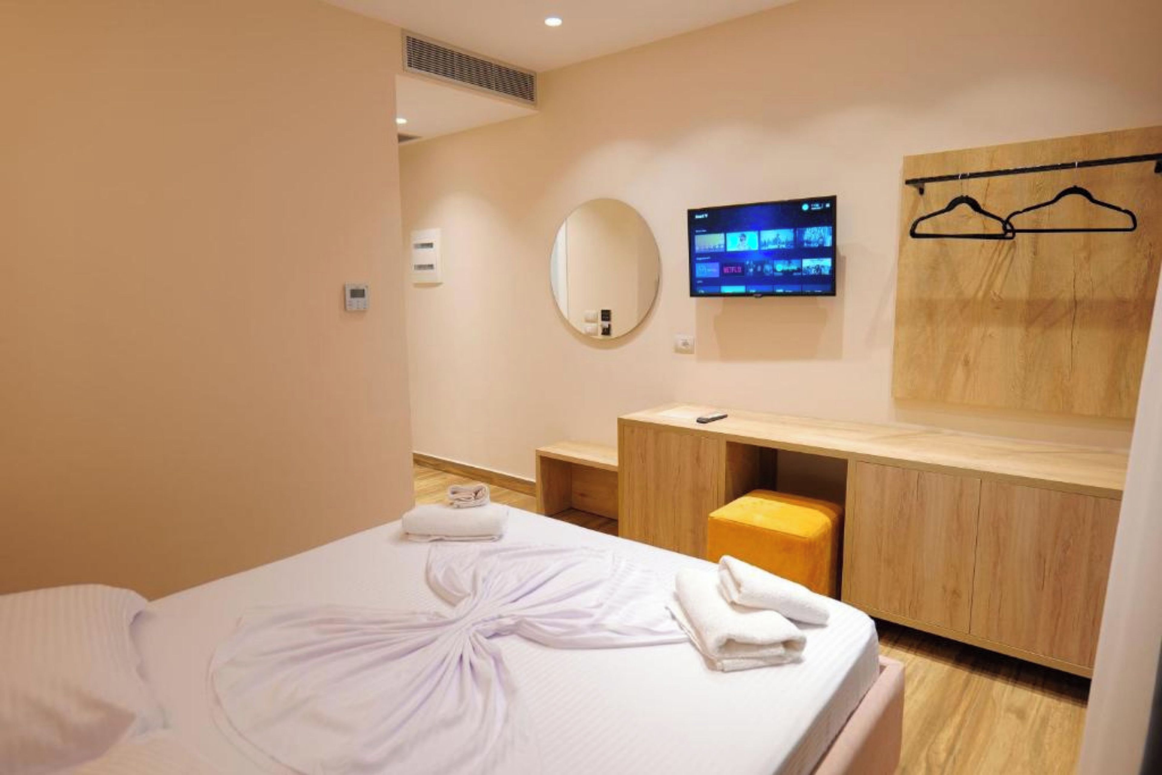 Habitació d'hotel amb llit, tocador de fusta amb mirall, televisió de pantalla plana i una banca de fusta.