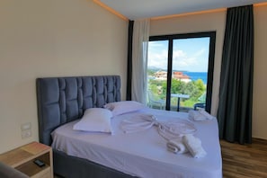 A hotel room with a large bed, a view of the sea, and a balcony.