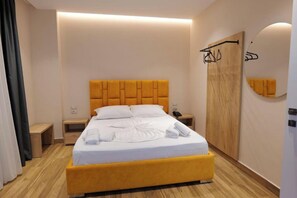 A hotel room with a bed, bedside tables, a wardrobe, and a mirror. - Hotel Alexander (Sarandë)