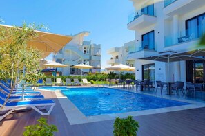 A modern hotel with a swimming pool, outdoor seating, and a clear blue sky. - Hotel Alexander (Sarandë)