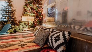 Un salon chaleureux avec un sapin de Noël, un tapis à motifs et un canapé en cuir.