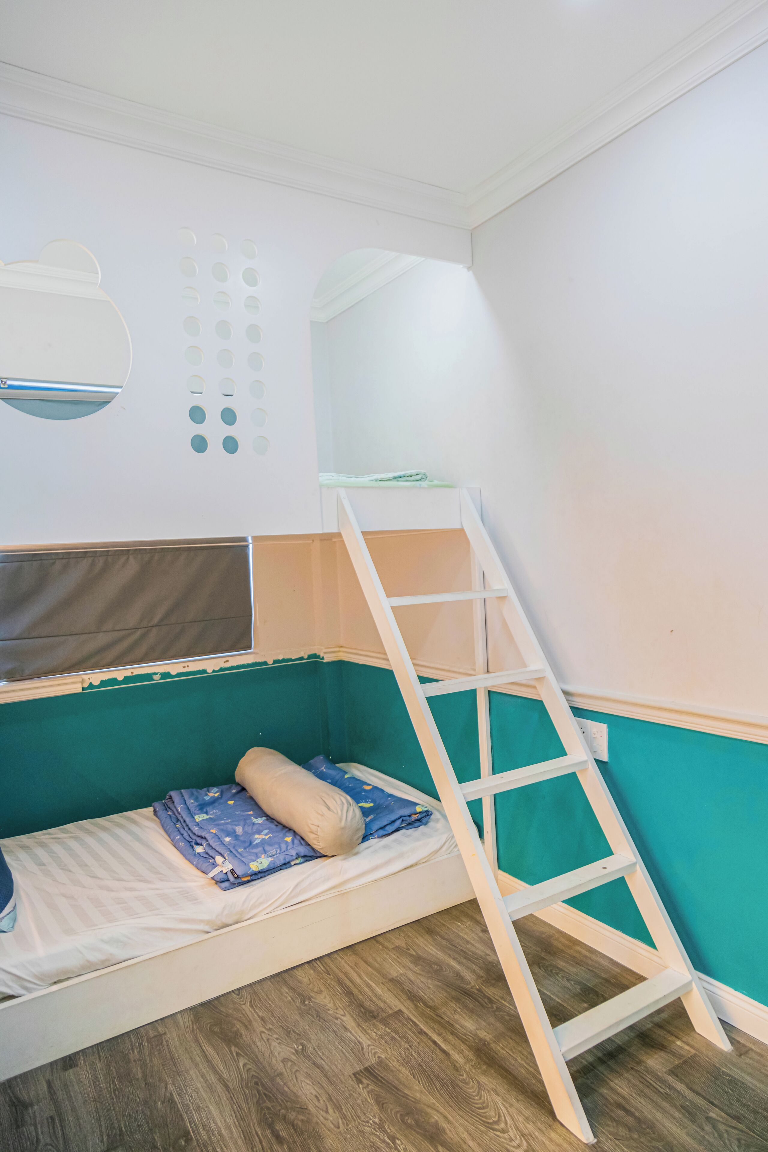 Una cama litera con escalera, un escritorio pequeño y un estante fijado a la pared.