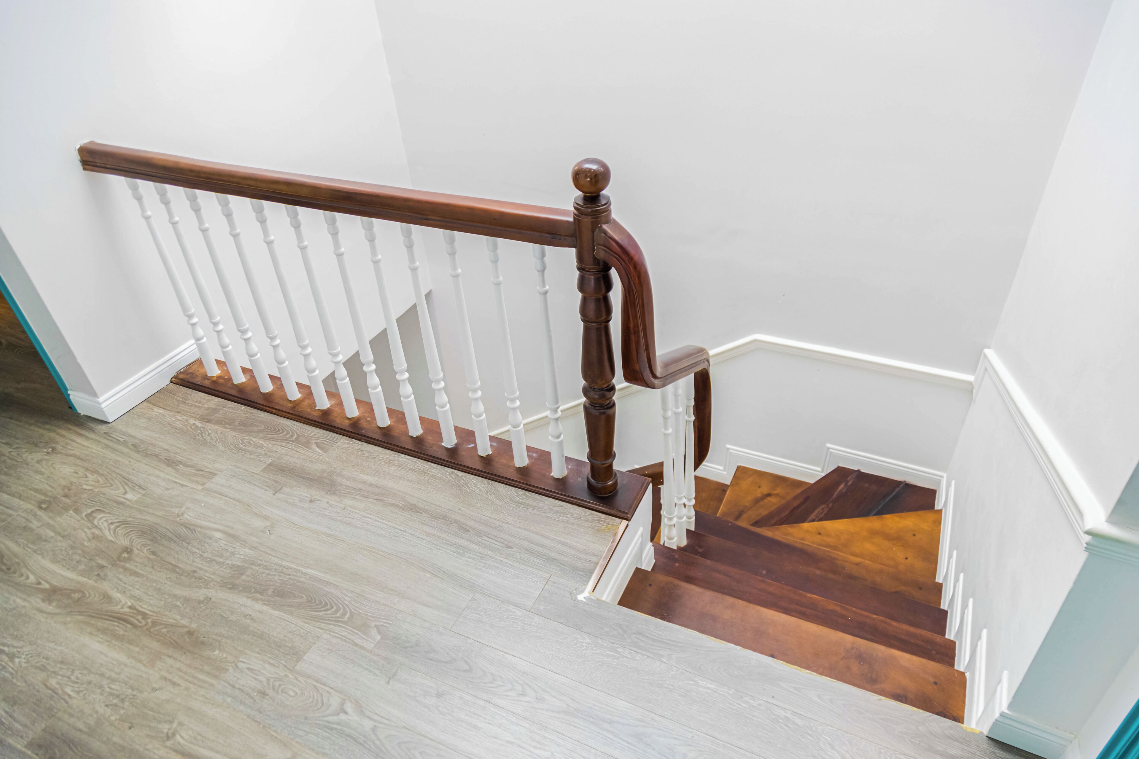 A wooden staircase with white balusters and a dark wood handrail.