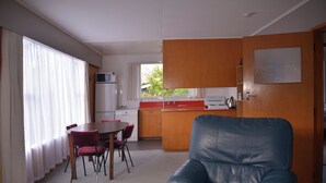Un espacio habitable compacto con comedor, kitchenette y sofá de cuero azul.