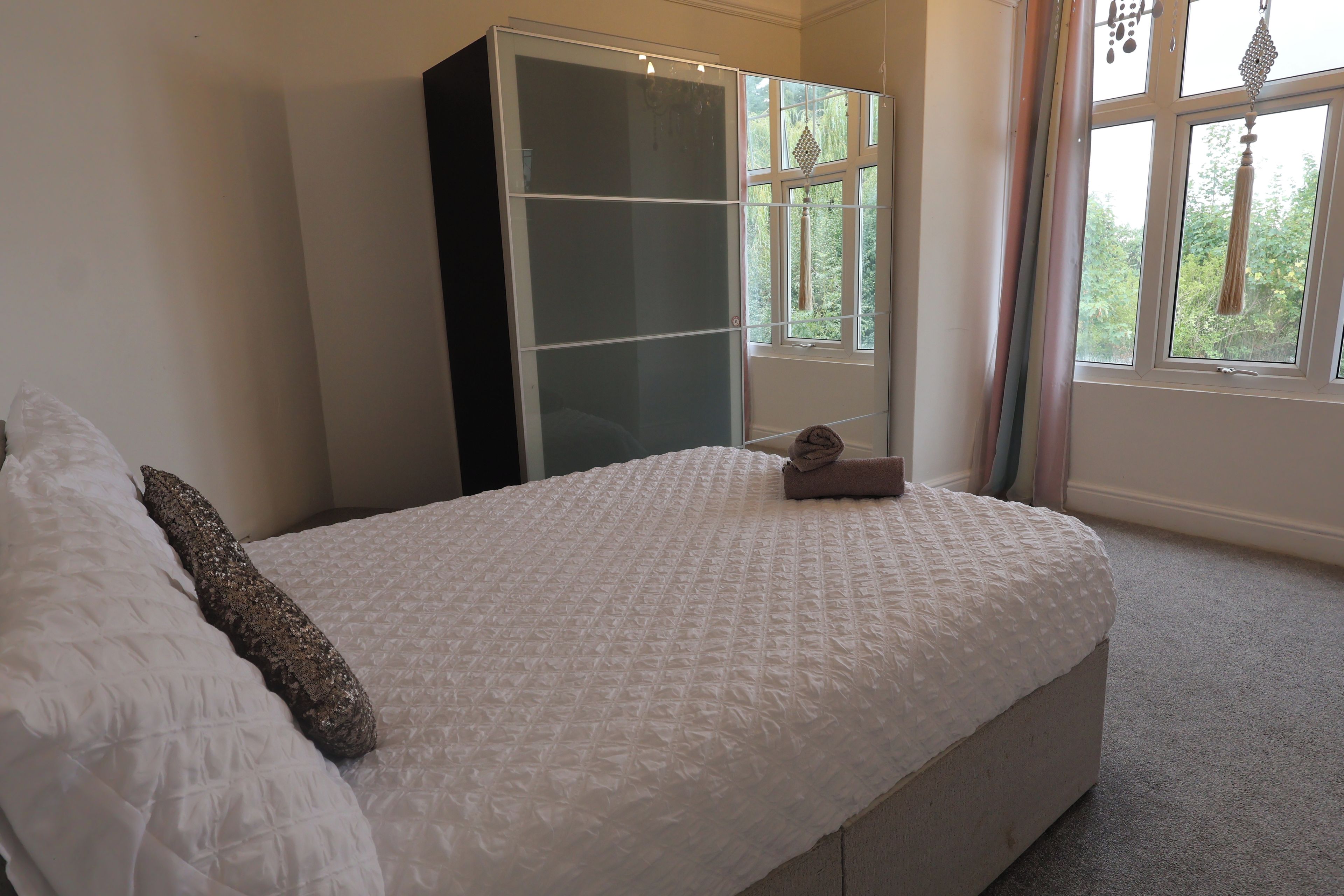 A bedroom with a bed, a wardrobe, and a window with curtains.