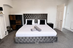 Ein Schlafzimmer mit einem großen Bett, einem Kopfteil und einem Nachttisch.