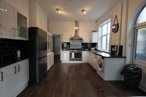 A modern kitchen with a central island, stainless steel appliances, and a large window. - The Shobnall House - Newly Refurbished, 5 Bedrooms (Burton on Trent)