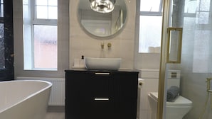 Moderni kylpyhuone, jossa on erillinen kylpyamme, tyylikäs allas ja wc-istuin.