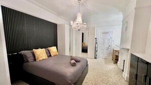 Un dormitorio con cama, candelabro, chimenea y espejo.