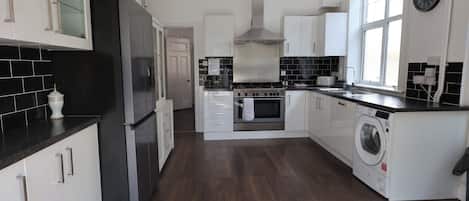 Una cocina moderna con un refrigerador de acero inoxidable, un horno empotrado y una lavadora.