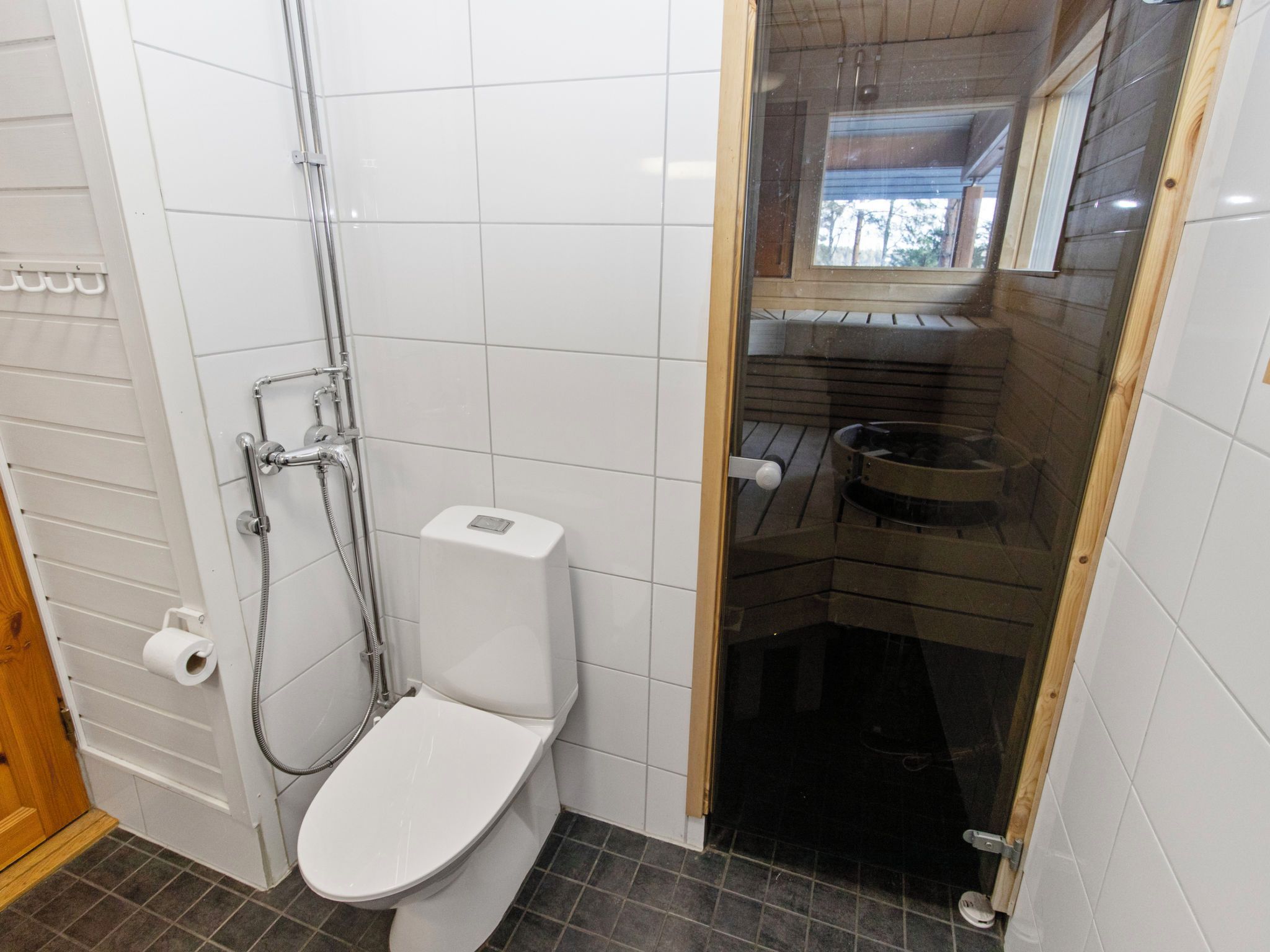 A bathroom with a white toilet, a shower with a glass door, and a visible toilet paper holder.